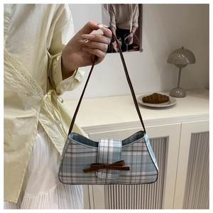 Detail of blue plaid canvas shoulder bag with brown bow and leather strap detail
