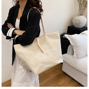 Detail of beige canvas tote bag showing high-capacity design and 3D textured embroidery