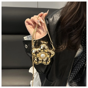 Detailed close-up of golden flower mini bag with white pearl and fine metal chain