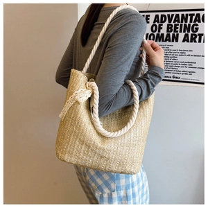 Detail shot of straw woven tote with white lace bow and thick rope handle for beach use