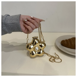Detail of flower-shaped gold metal mini bag with large central pearl and snake chain