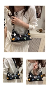 Detail of black crocodile pattern bag with colorful plush flowers and silver chain strap