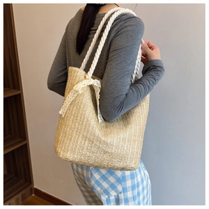 Detail of hand-woven straw tote bag with white lace bow and cotton rope shoulder straps