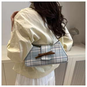 Detailed back view of a plaid baguette bag with bow detail on a model in warm light
