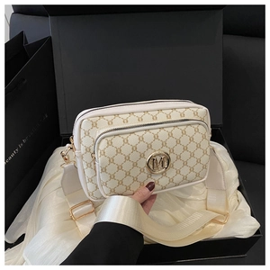 Detail of retro ivory crossbody bag with golden M logo and wide fabric strap in a gift box