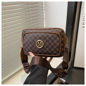 Close-up of vintage camera bag with hexagonal monogram pattern and gold M logo