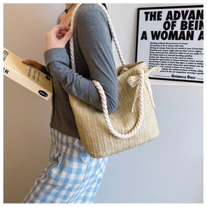 Detail of straw tote bag featuring rope handles and a white lace bow decoration