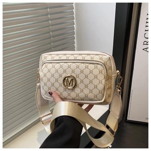 Detail of vintage patterned crossbody bag with golden M logo and wide shoulder strap