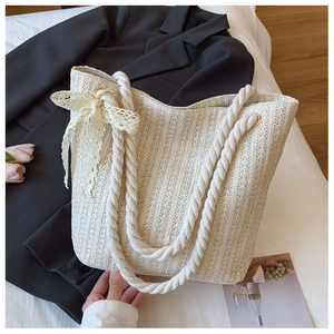 Detailed texture of beige woven straw tote bag with lace bow and soft cotton rope handle