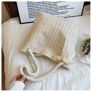 Close-up of cream woven tote bag with intricate lace bow detail and rope handles