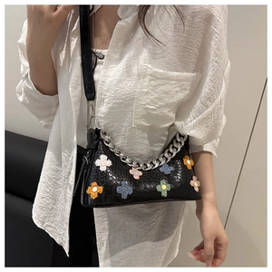 Detail view of black crocodile pattern shoulder bag with colorful plush flowers and silver chain