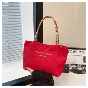 Close-up of red canvas handbag featuring rainbow woven rope handles and button closure