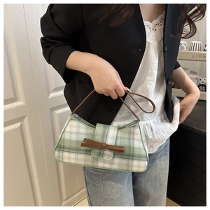 Green and white plaid underarm bag featuring a brown leather bow and slim shoulder strap
