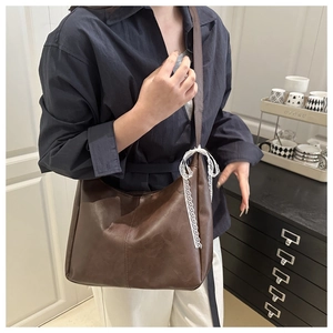 Detail der dunkelbraunen Ledertasche mit weißer Spitzenschleife am Schultergurt im Alltag