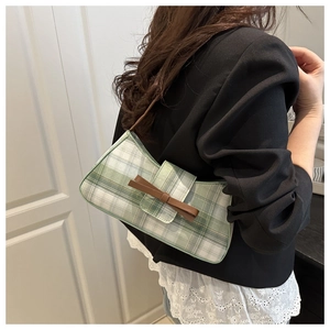 Green and white checkered underarm bag with brown leather bow detail worn by model