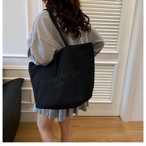 Detail of minimalist black tote bag with embossed lettering on high-quality fabric