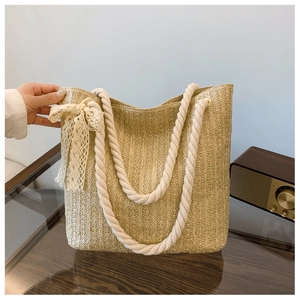 Detail of hand-woven straw tote bag with lace bow and thick cotton rope handles