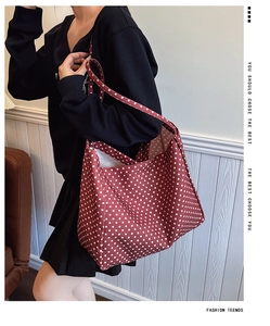 Detail of red canvas tote bag with white polka dots and long shoulder straps for daily use
