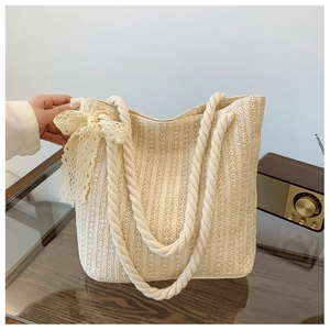 Detail of off-white straw tote bag with cotton rope handles and lace bow decoration