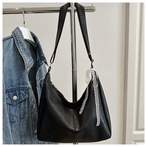 Detail der schwarzen Hobo-Tasche mit weißem Spitzenband am Metallständer