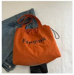 Detail of orange drawstring bucket bag with Fanyissa logo on textured white background
