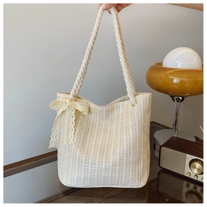 Detail of cream woven tote bag with texture and a delicate lace bow accent