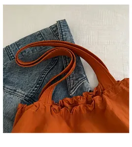 Detail of orange nylon tote bag featuring ruffled elastic top and comfortable handles