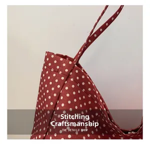 Detailed view of reinforced double stitching and seam quality on red polka dot canvas bag