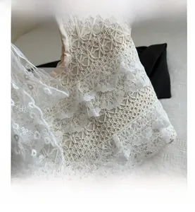 Close-up of intricate beige lace floral patterns and ruffled edges on a tote bag
