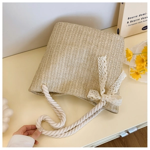 Close-up of woven straw bag texture with white cotton rope handle and lace bow detail