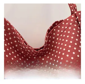 Detail shot of red canvas tote bag with white polka dots showing fabric texture and stitching