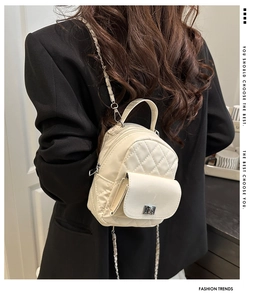 Detail eines cremefarbenen gesteppten Mini-Rucksacks mit Metallkette und Drehverschluss