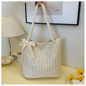 Detail of woven straw tote bag with lace bow decoration and sturdy hemp rope handles