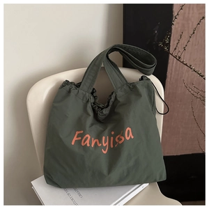 Detail of dark green canvas tote with orange logo print and drawstring closure