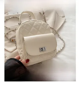 Close-up of beige quilted mini backpack with silver metal chain and twist-lock detail