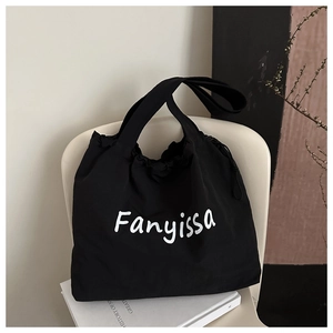 Detail of black canvas tote bag featuring adjustable drawstring and Fanyissa logo on a chair