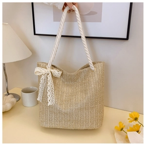 Detail of woven straw tote bag with delicate lace bow and white cotton rope handles