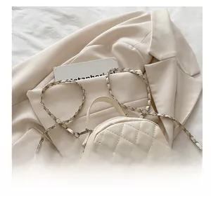 Close-up of beige quilted crossbody bag with metal twist lock on a neutral blazer