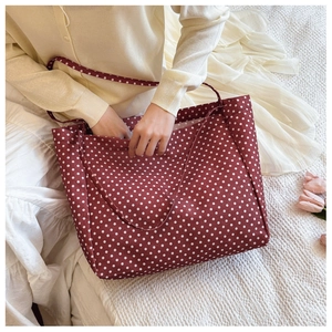 Close-up of red polka dot canvas tote bag shown in a cozy aesthetic lifestyle setting