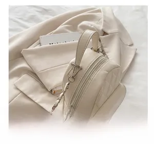 Detailed view of beige quilted mini backpack with silver metal hooks and chain strap