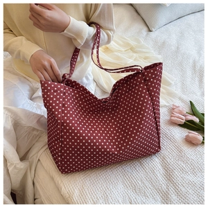 Detailed texture of red polka dot canvas tote bag shown in a cozy home setting