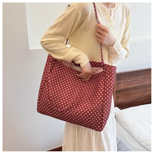 Detailed view of large red canvas tote bag with white polka dots worn on the shoulder