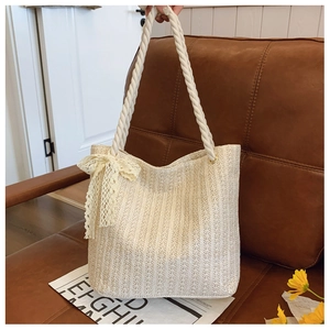 Detail of woven straw tote bag with rope handles and a decorative lace bow accent