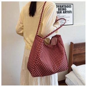 Detail of red and white polka dot canvas tote bag with slim straps in a lifestyle setting