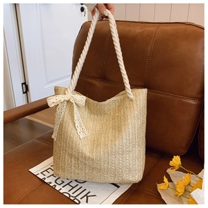 Detailed close-up of woven straw handbag with white rope handles and lace bow decoration
