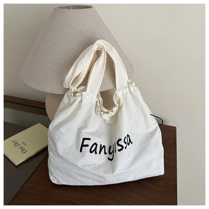 Detail of white nylon tote bag featuring black Fanyissa print and pleated drawstring design