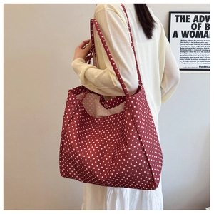 Detail of burgundy polka dot canvas tote bag showing the magnetic snap button closure
