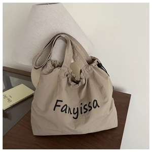 Detail of khaki drawstring tote bag with Fanyissa logo on a cozy wooden table setup