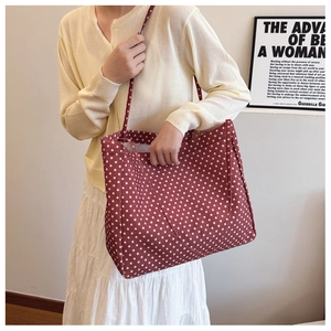 Detail of red canvas tote bag with white polka dots featuring large capacity shoulder straps