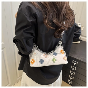 Detail of white crocodile texture leather shoulder bag with colorful floral charms and chain